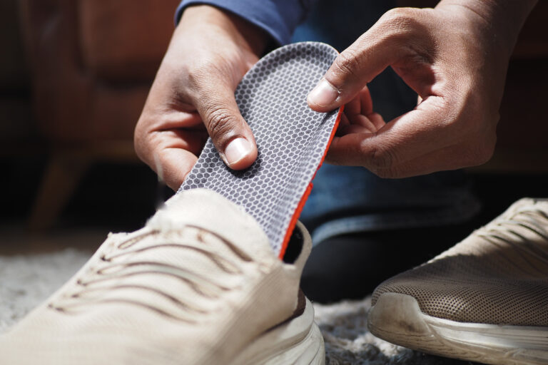 men hand putting Orthopedic insoles in shoes .